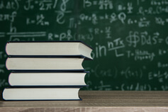 книги по математике на фоне доски
