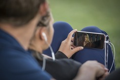 Девушка в наушниках смотрит видео на смартфоне.