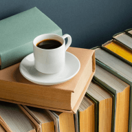 Чашка кофе на блюдце, расположенная на верхней книге в стопке книг с разноцветными обложками